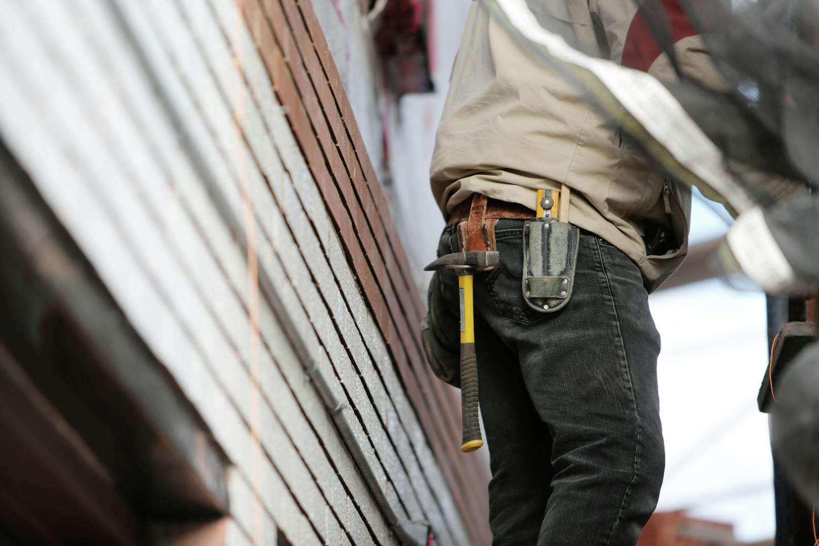 builders risk, lose-up of a construction worker with hammer and tools, focused on the job.